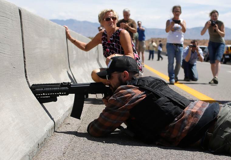 Image: A protester aims his weapon from a bridge next to the Bureau of Land Management's base camp where seized cattle, that belonged to rancher Cliven Bundy, are being held at near Bunkerville