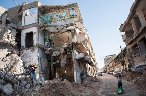 GAZA, PALESTINIAN TERRITORY - DECEMBER 2: A child passes a bombed-out residential block in the Al-Zeitoun neighborhood of Gaza City, December 2, 2012.